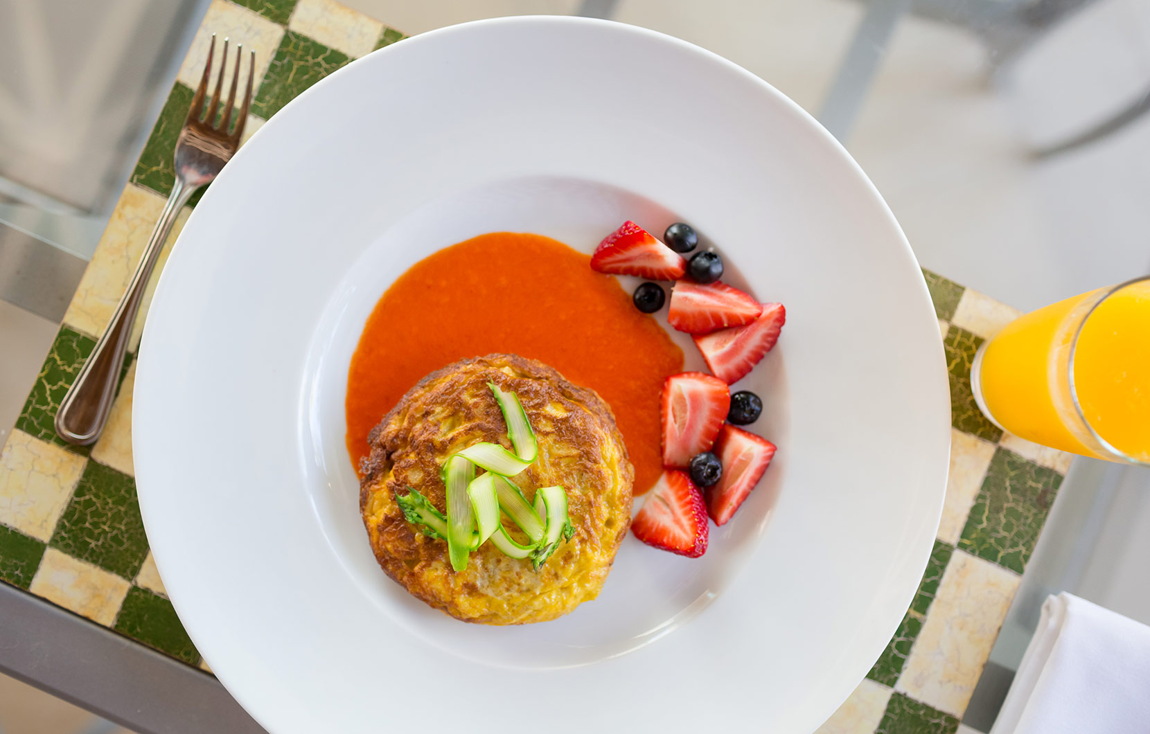 Spanish tortilla with tomato coulis, a side of fresh berries, and a just-squeezed juice.